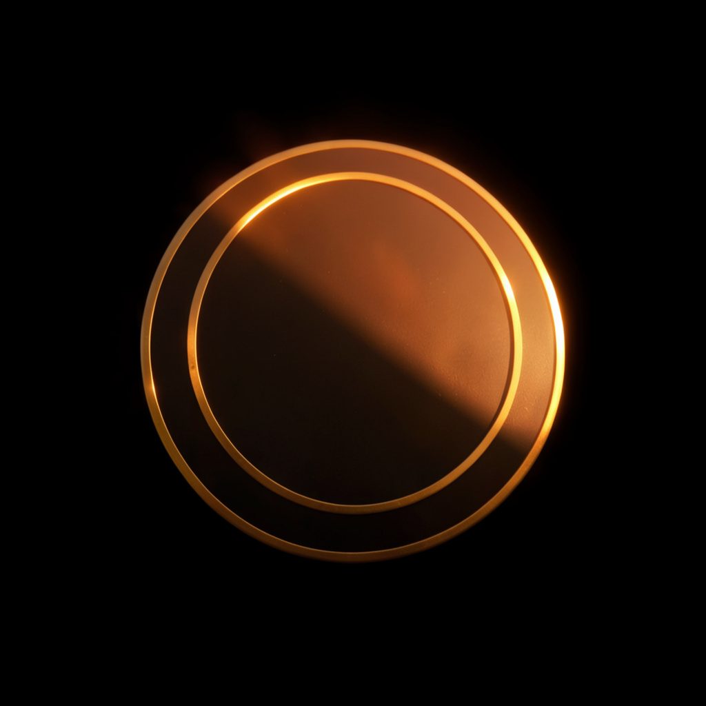 Dark circular emblem with a subtle golden rim, set against a near-black background