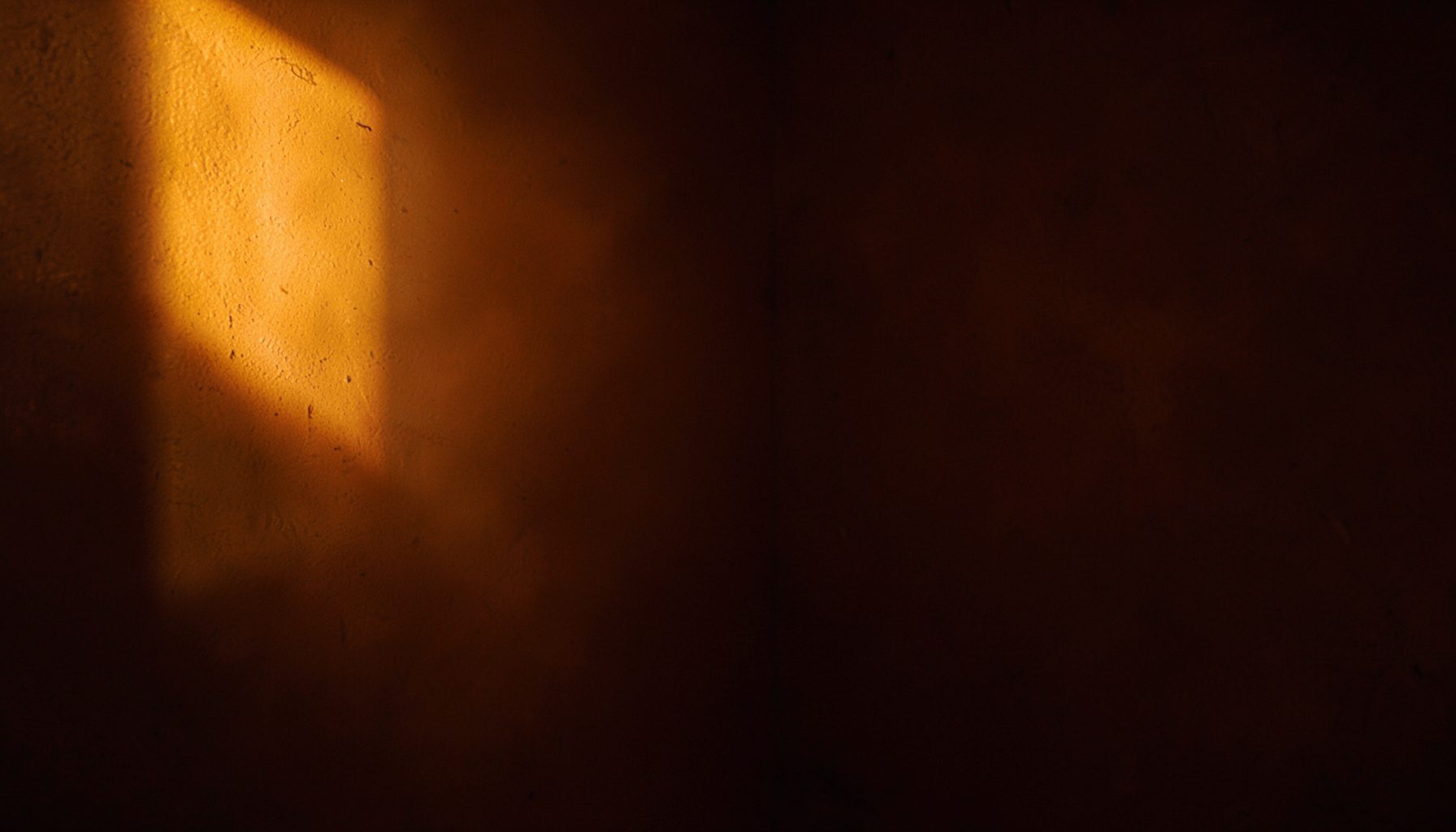 Warm amber glow illuminating a dark corner, casting long gentle shadows