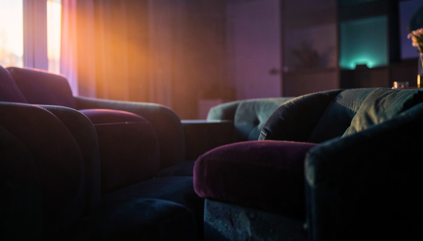 Soft purple and teal ambient light in a dark lounge setting with plush textures