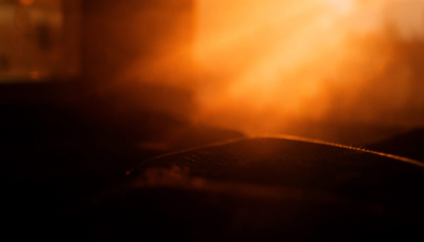 Warm amber light spilling across a dark surface, creating a cozy evening mood