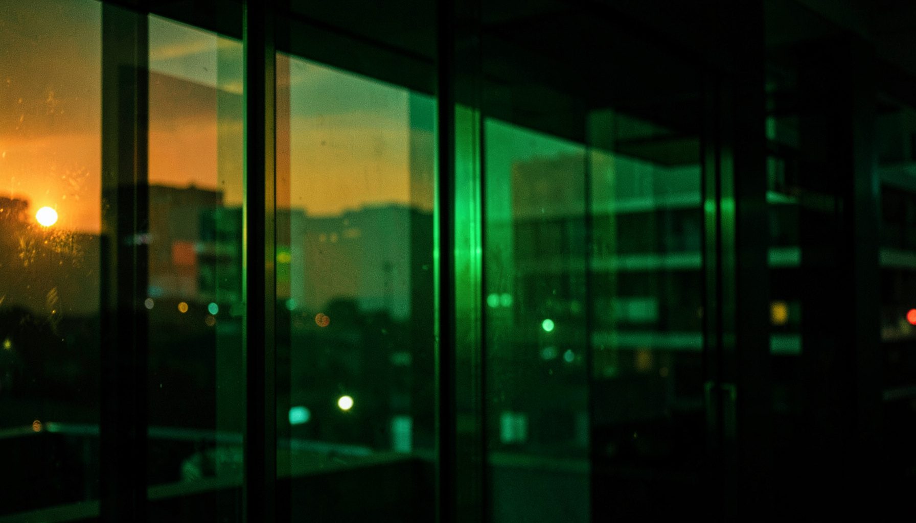 Deep green and teal nightlife lighting reflected in dark glass surfaces