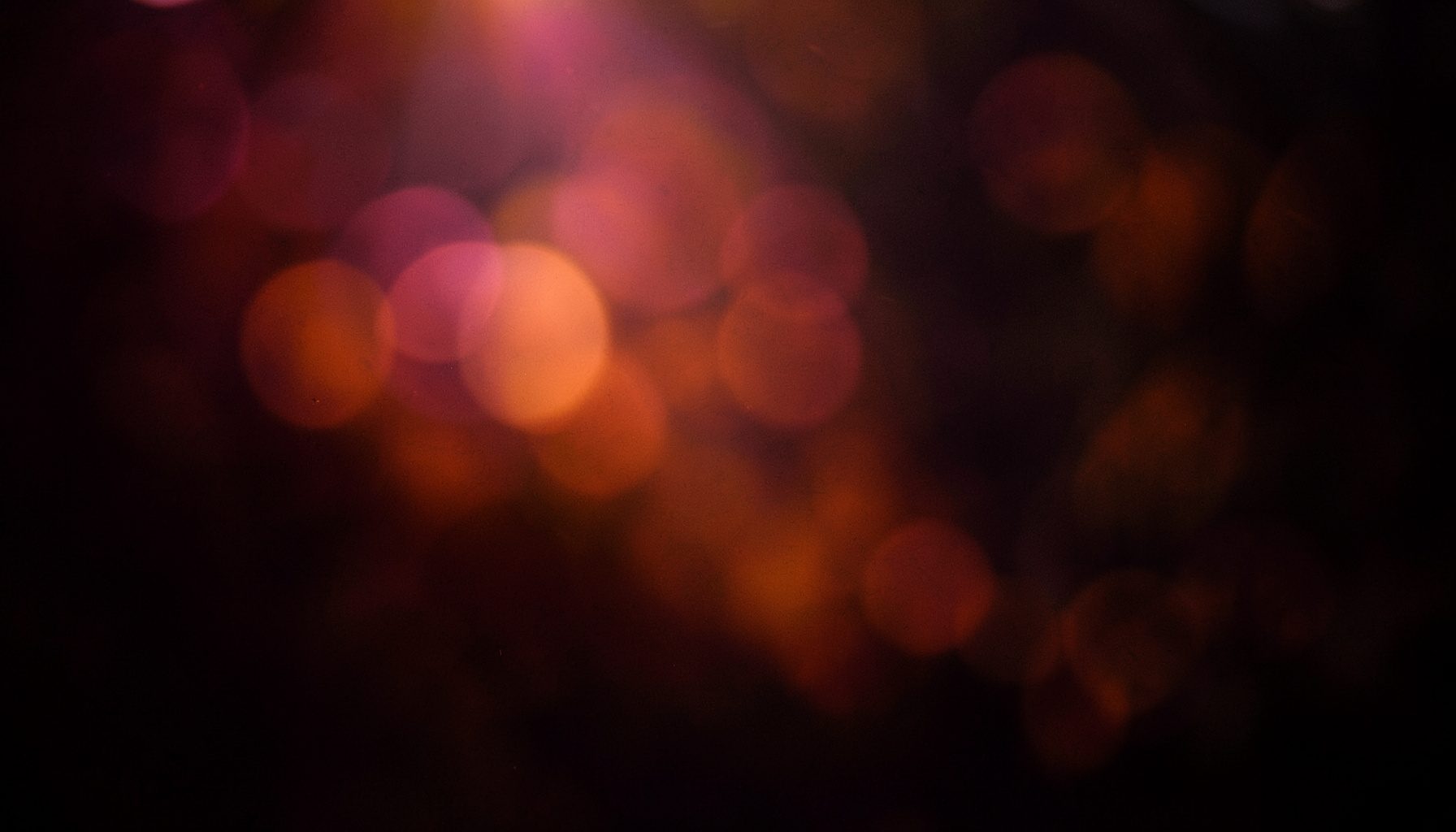 A dark scene with subtle magenta and amber highlights, soft bokeh circles in the background