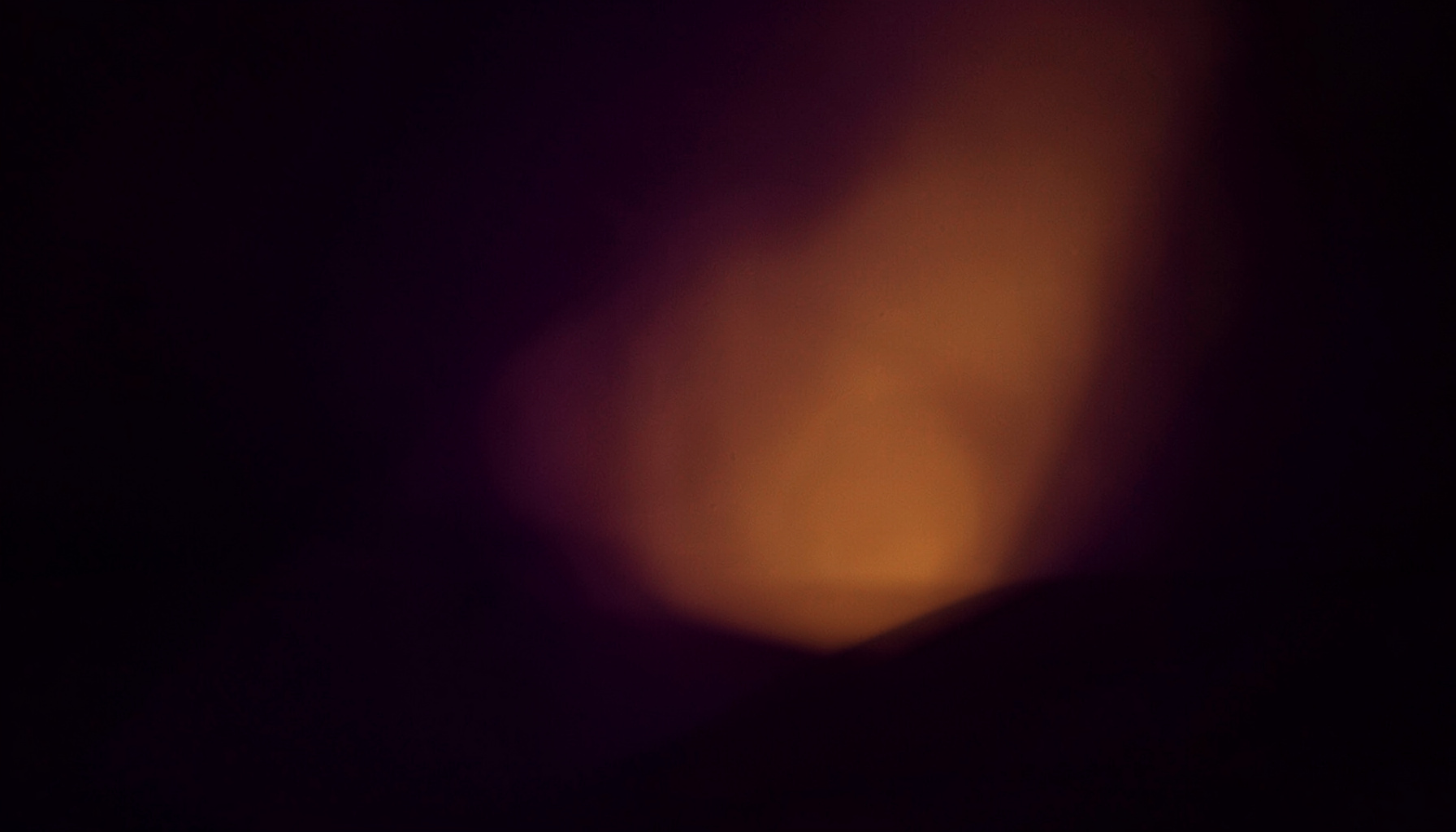 Deep purple shadows and a single warm golden light source in a minimalist dark setting
