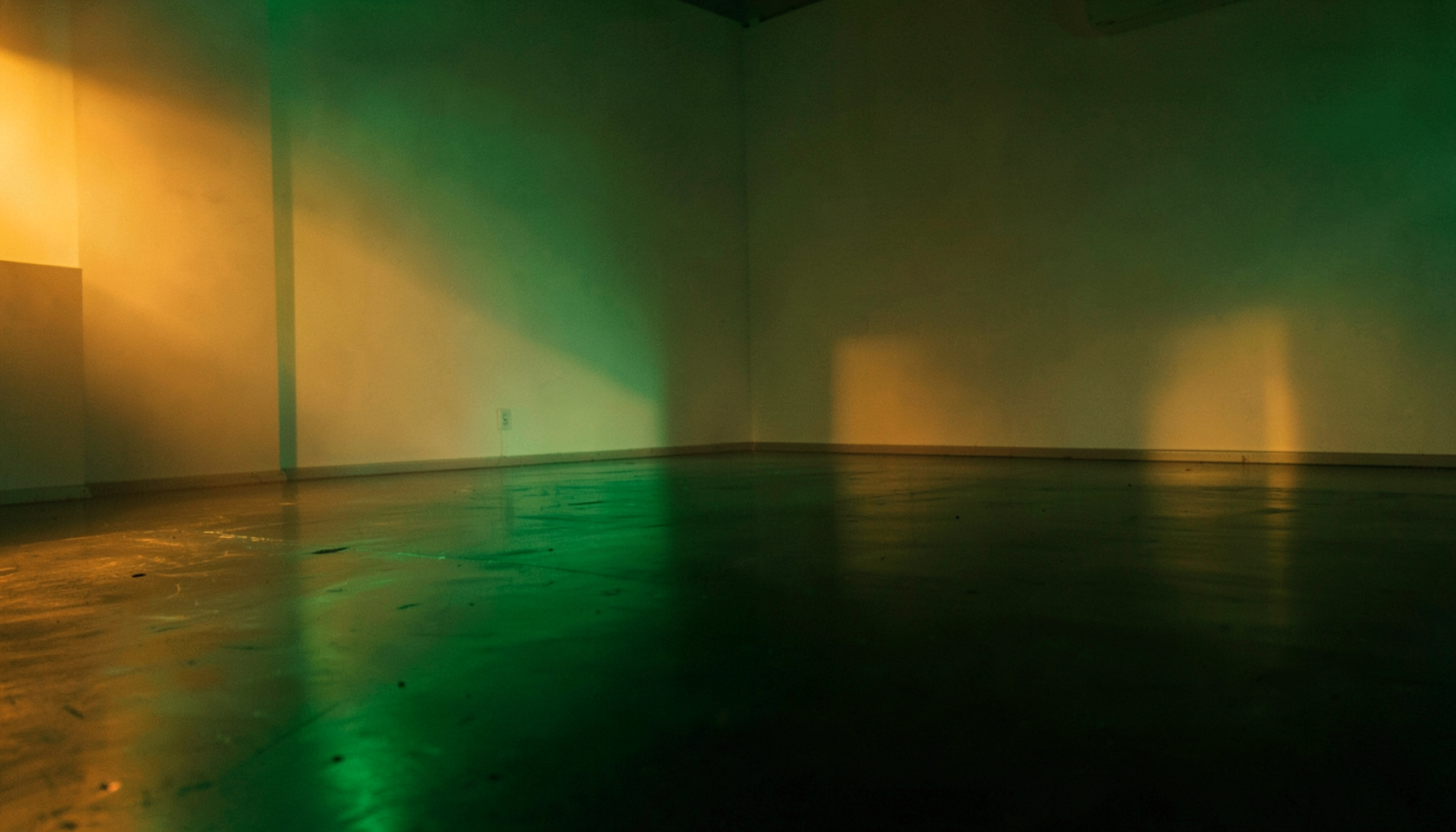 Teal and green neon glow reflecting off a dark glossy floor in an empty room
